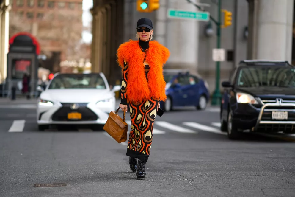 žena v chlupaté oranžové vestě ve městě