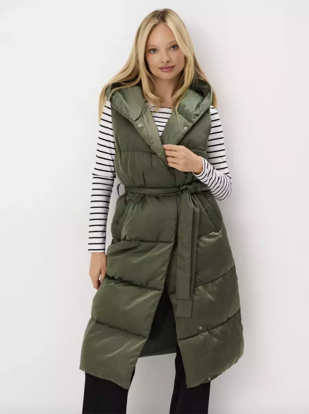 žena v prošívané dlouhé vestě s páskem