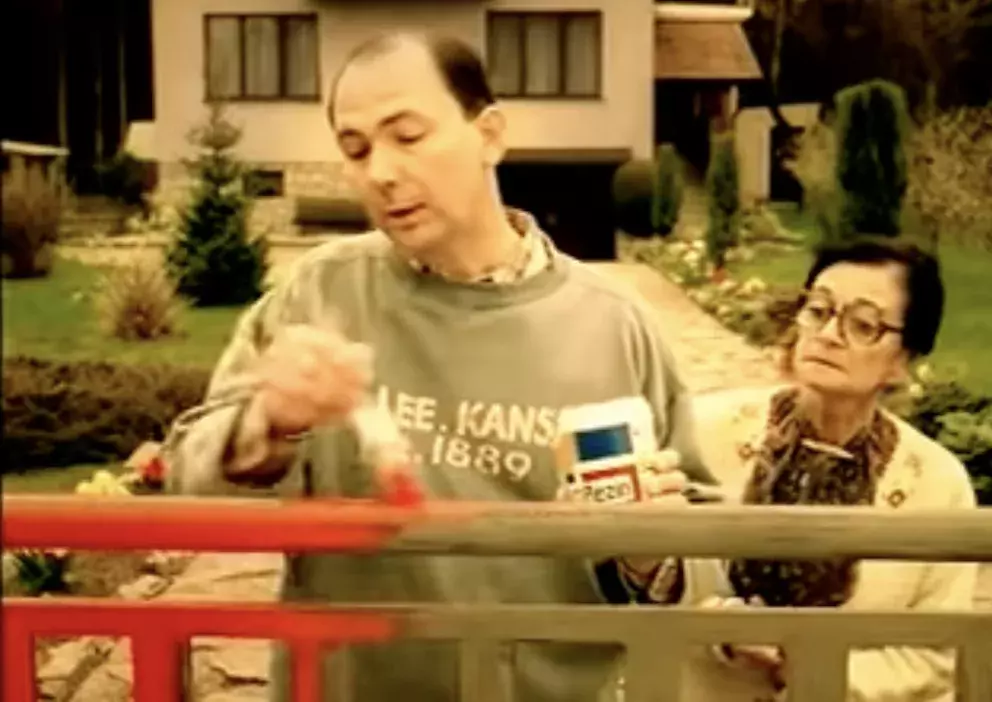 muž natírá plot pod dohledem tchyně