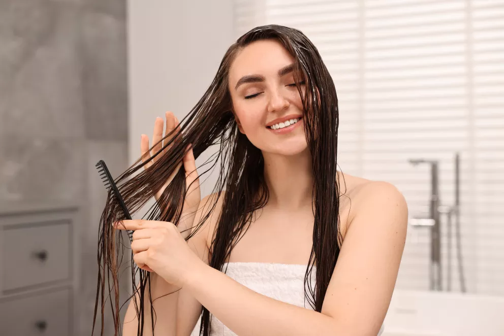 žena rozčesávající si umyté vlasy