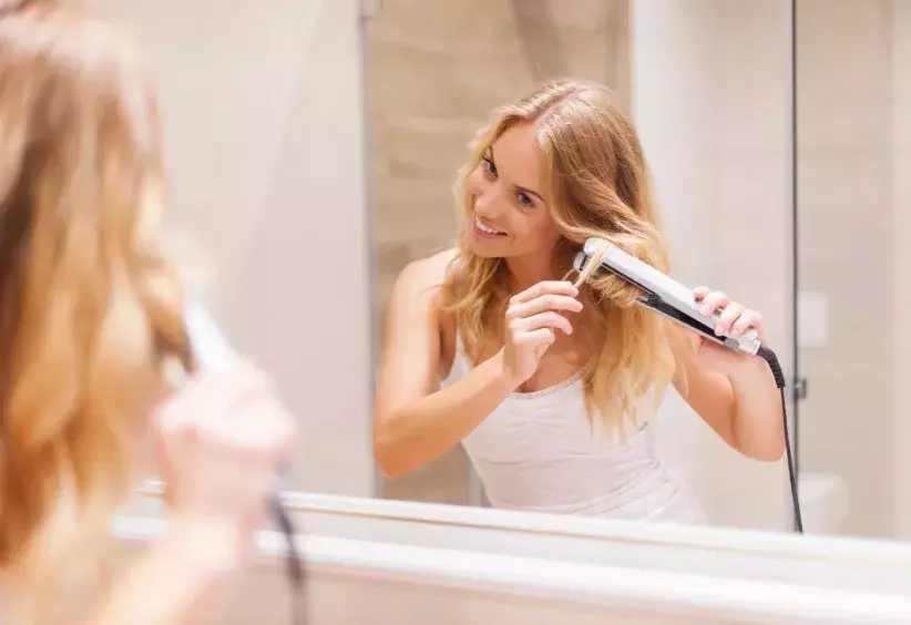 žena si žehlí vlasy