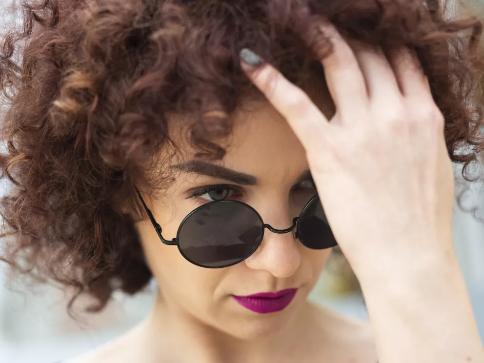 žena s kudrnatými vlasy a slunečními brýlemi